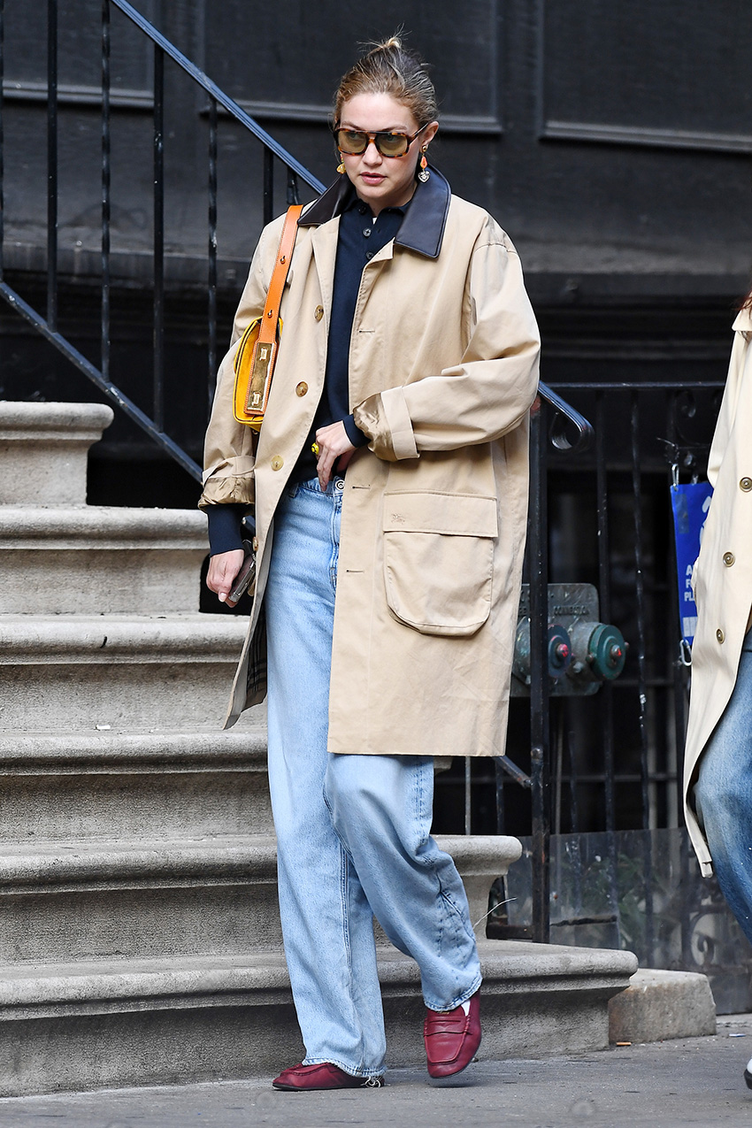 Gigi Hadid wearing a trench, polo top, light-wash jeans, and red Miu Miu loafers