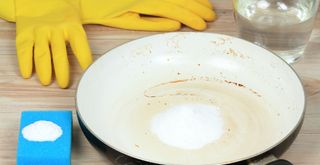 Saucepan with blue sponge and baking soda to show how to clean a burnt pan with baking soda and vinegar