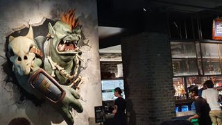 A sculpted troll bursts out of a wall next to a bar