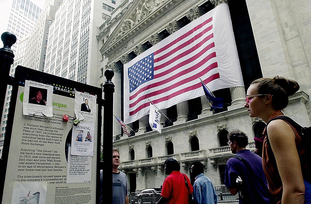 Residents walk by posters for victims of the World Trade Center outside the New York Stock Exchange on September 24, 2001, after the opening bell in New York.