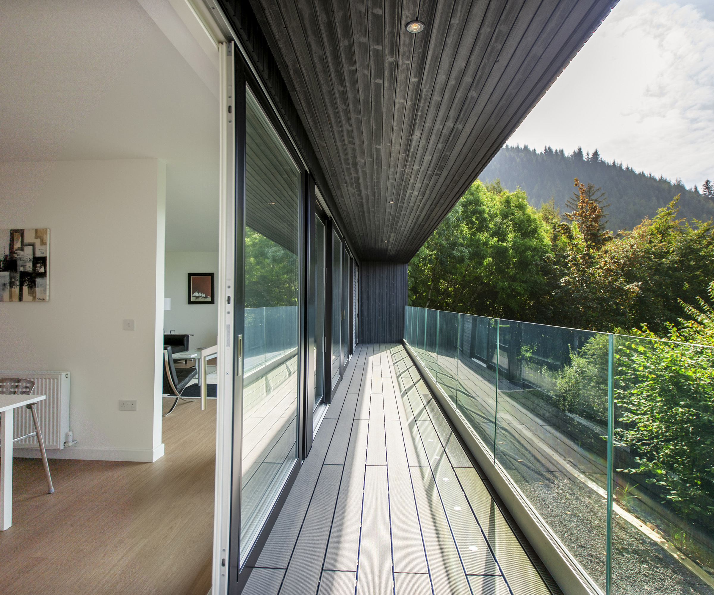 A long balcony walkway along the length of a self build home in the hills