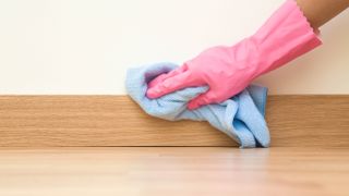 Wiping baseboard with a blue cloth