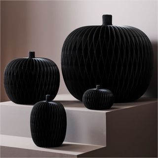 Decorative Spooky Paper Pumpkins against a gray wall.