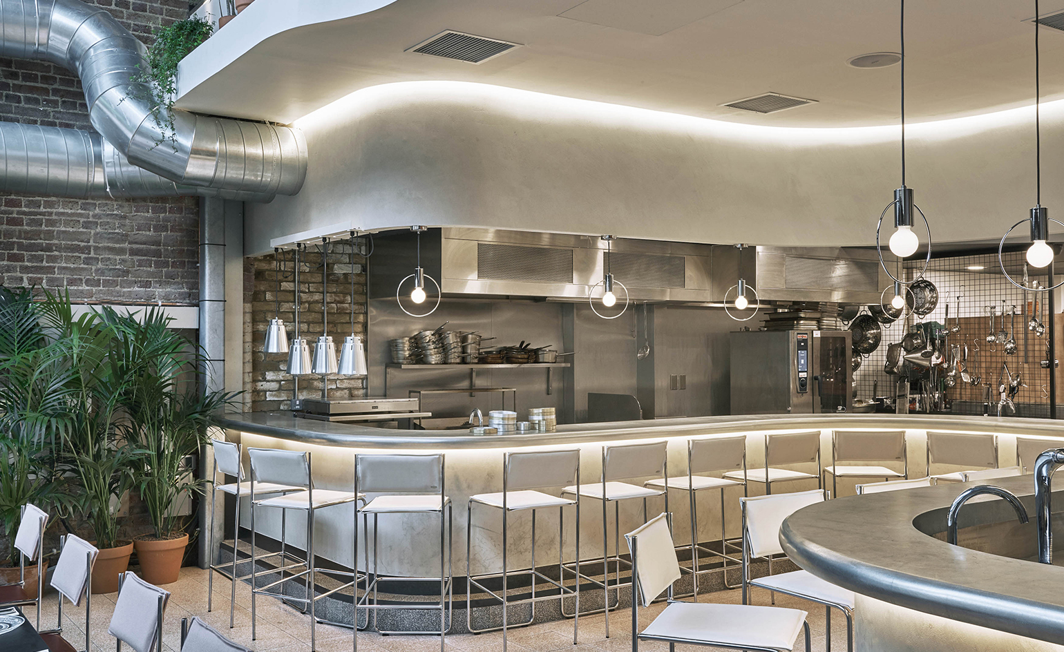 Bala Baya kitchen with dining counter and leather and chrome stools, palm fronds in terracotta pots