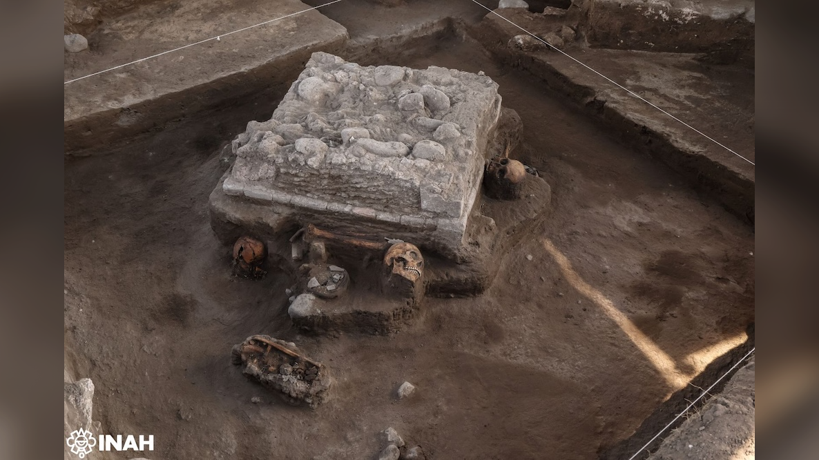 a square stone altar with human skulls surrounding it is being excavated by archaeologists