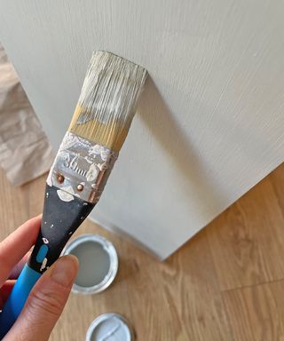 paintbrush with pale green paint on a piece of wood