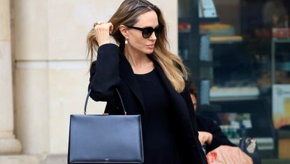 Angelina Jolie wears a celine bag black coat and drop earring while running errands