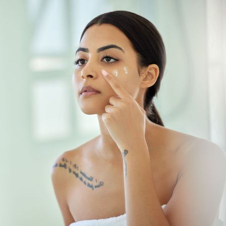 woman applying one of the best sunscreen for acne-prone skin - getty images 1389859311