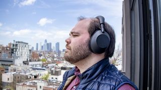 A man wearing black Sony WH-1000XM6 noise-cancelling headphones