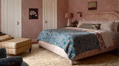 pink wallpapered bedroom with vintage style, a vintage rug and yellow patterned armchair and ottoman