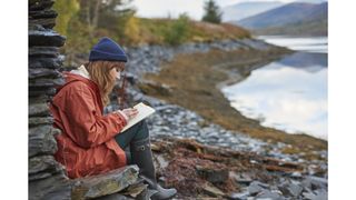 Woman nature journaling by water