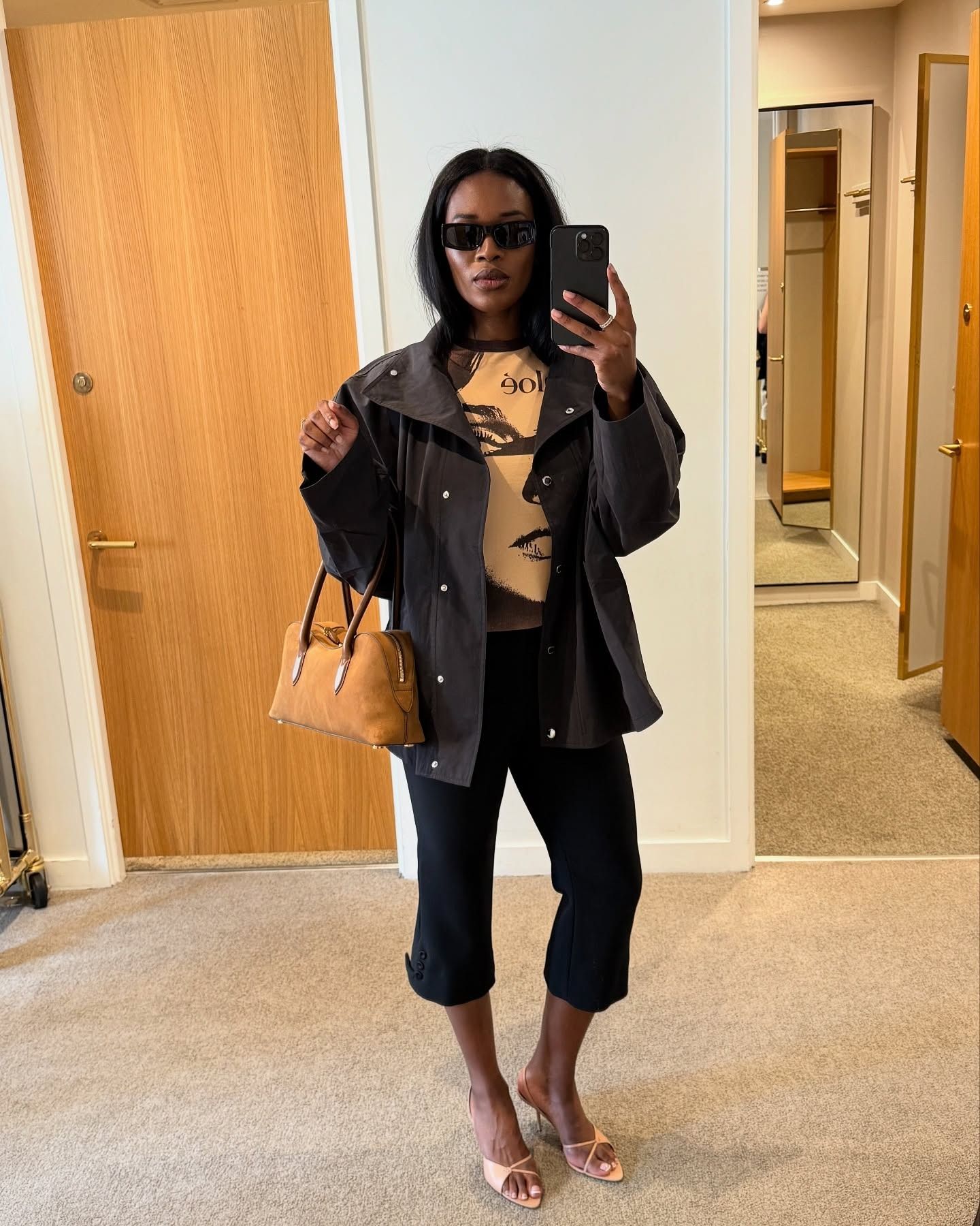 @nlmarilyn wearing a jacket, graphic tee, pedal pushers, and orange peep-toe heeled sandals.
