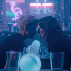 mae martin and charlotte ritchie lean in to kiss at a bar on the tv show feel good