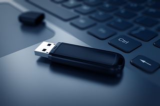 A USB drive positioned on the keyboard of a laptop