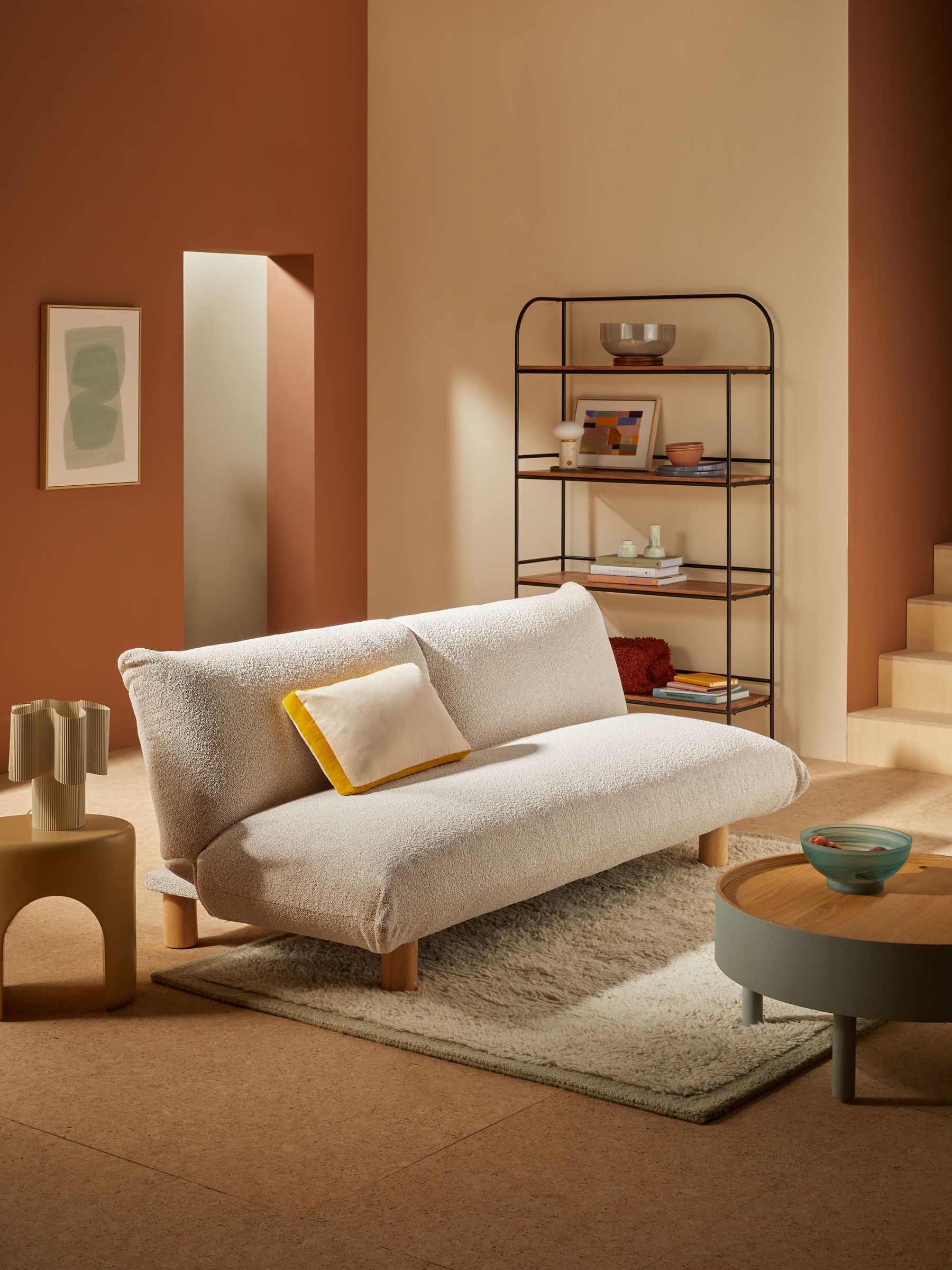Jude 3 Seater Sofa Bed in Off White Pax Boucle sitting in a modern living room that has cork flooring and walls painted in a tonal terracotta color palette.