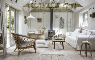 whitewashed living room with wall paneling, wood burner and natural furnishings and accessories