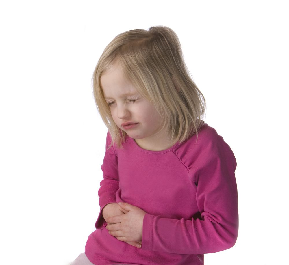 A little girl holds her stomach in pain.