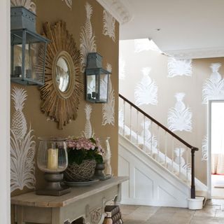Entrance hall with pineapple patterned wallpaper and oversized mirror