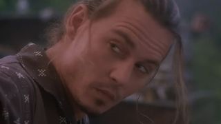 A close up of Johnny Depp with some hair over part of his face.