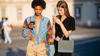 Two women looking down at their mobile phone screens