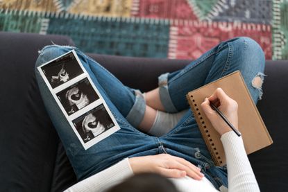 Stillborn stories: A pregnant woman looking at her baby photo and writing in a journal