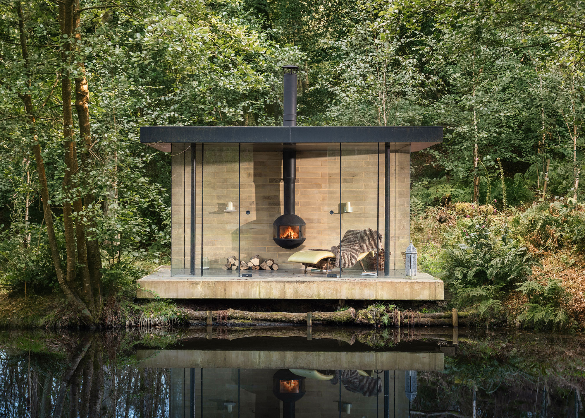 outdoor room with log burner and recliner overlooking water garden