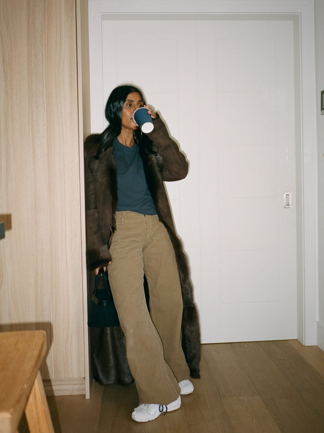 Influencer Monikh wearing corduroy trousers with a fur coat and white trainers.