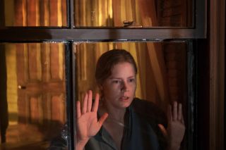 amy adams looks scared staring out a window in the woman in the window