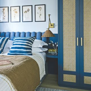 Blue bedroom with blue painted walls, a blue headboard, and a blue wardrobe with rattan frontage