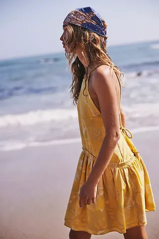 a model wears a yellow short dress on the beach
