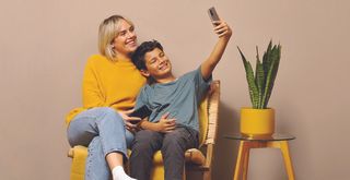 Gutt og kvinne med mobiltelefon i et arrangert stuemiljø.