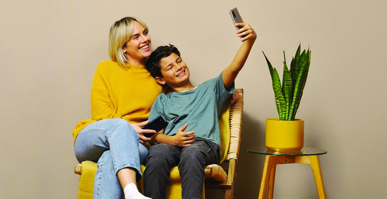 Gutt og kvinne med mobiltelefon i et arrangert stuemiljø.