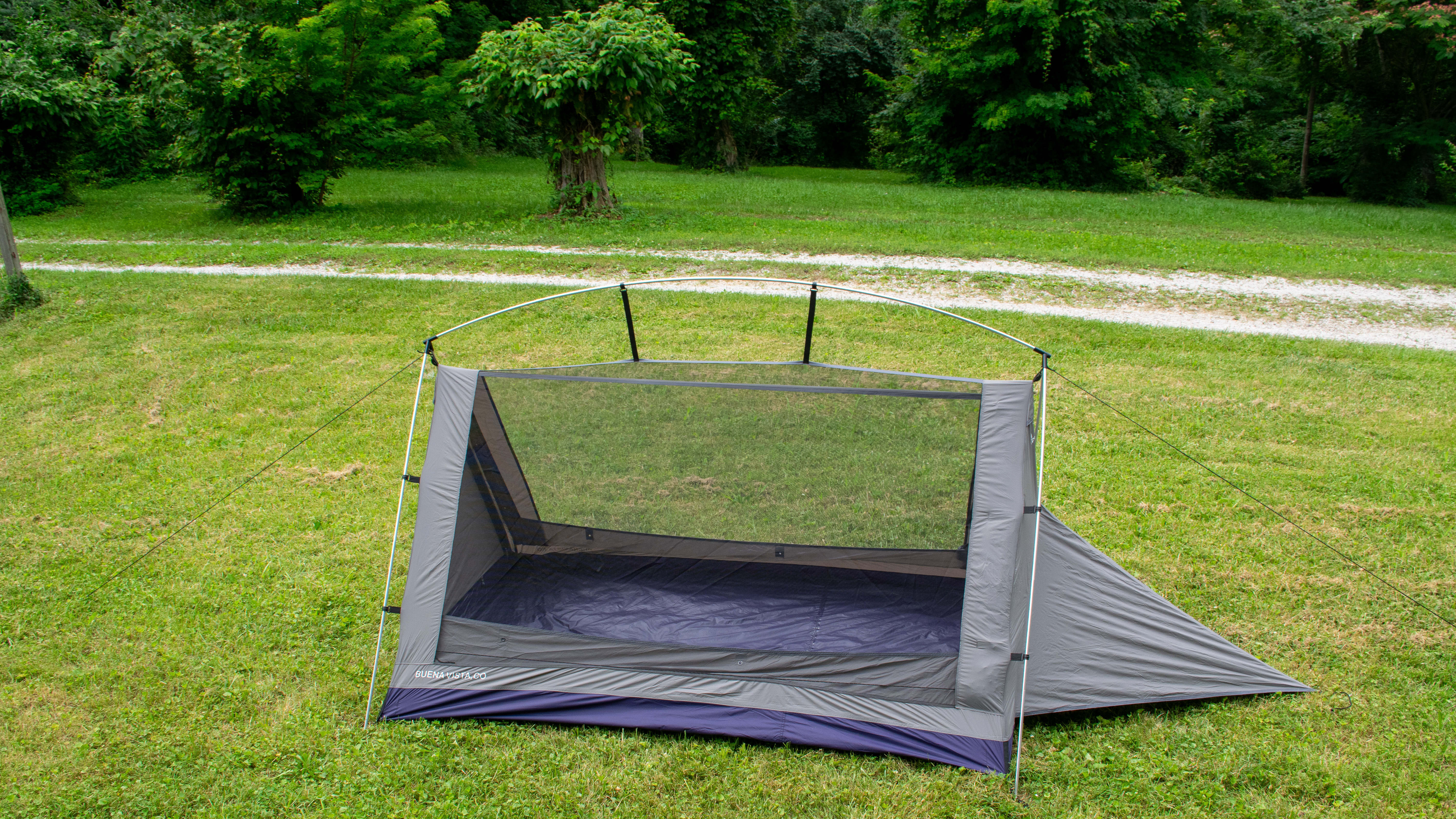 A tent with see-through roof sits on some grass next to a gravel drive.
