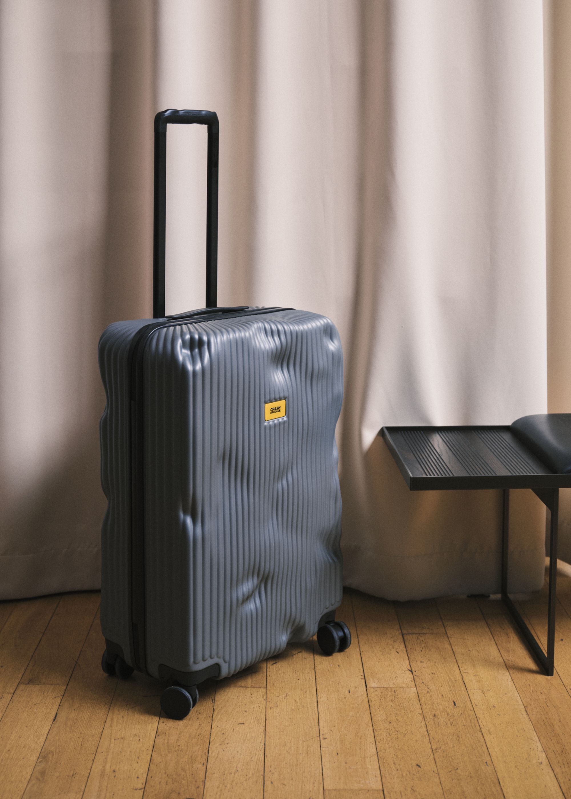 A blue striped hard shell suitcase from Crash Baggage