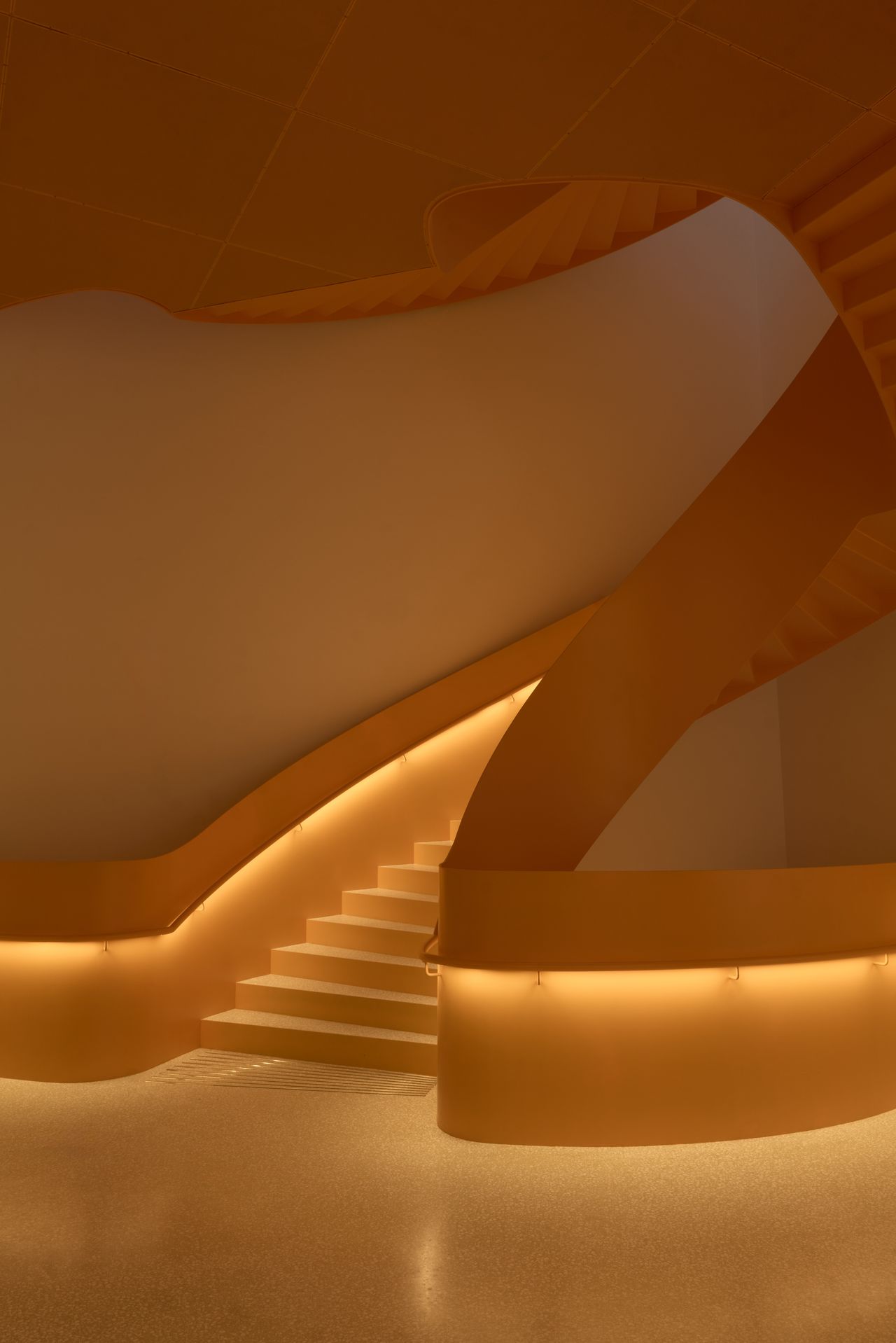 An orange, neon-lit surreal staircase features a sculptural, twisted design.