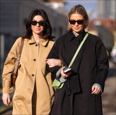Two women at Copenhagen Fashion Week wear neutral trench coats