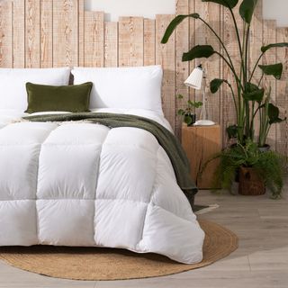 A bed with a white duvet on