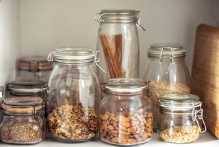 An array of glass jars containing cereals, nuts, seeds, and pastas.