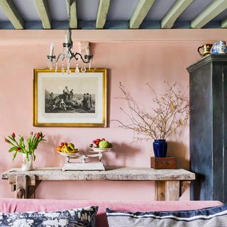 A pink living room with a grey ceiling and wooden beams