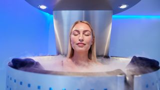 Woman in a cryotherapy chamber during treatment standing with eyes closed