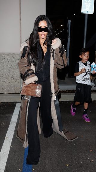 Kim Kardashian wearing a floor-length fur coat with an all-black outfit