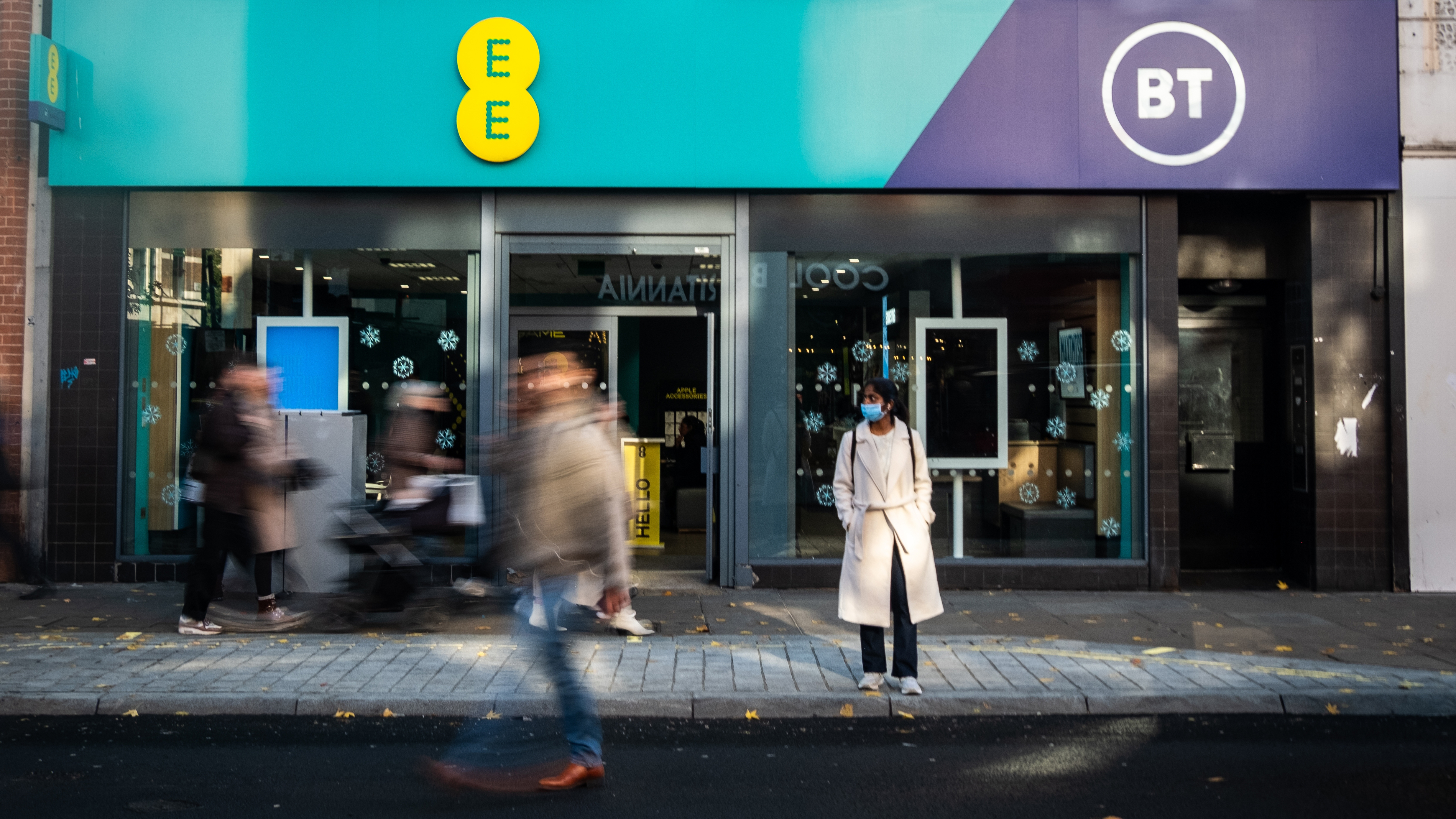 People walking in front of an EE and BT store