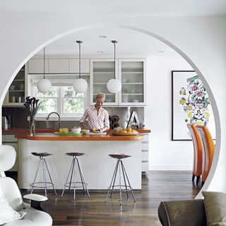 kitchen archway white wall lady at white counter wooden floor