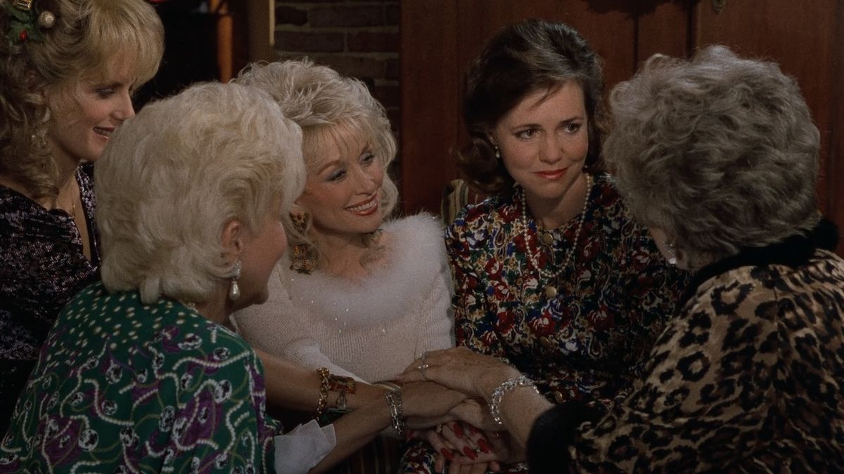 The women in Steel Magnolias piling their hands together and smiling in Steel Magnolias