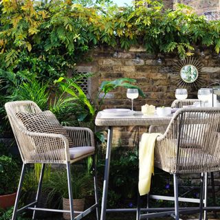 garden bar stools with high table, rattan style, yellow throw, starburst mirror on wall