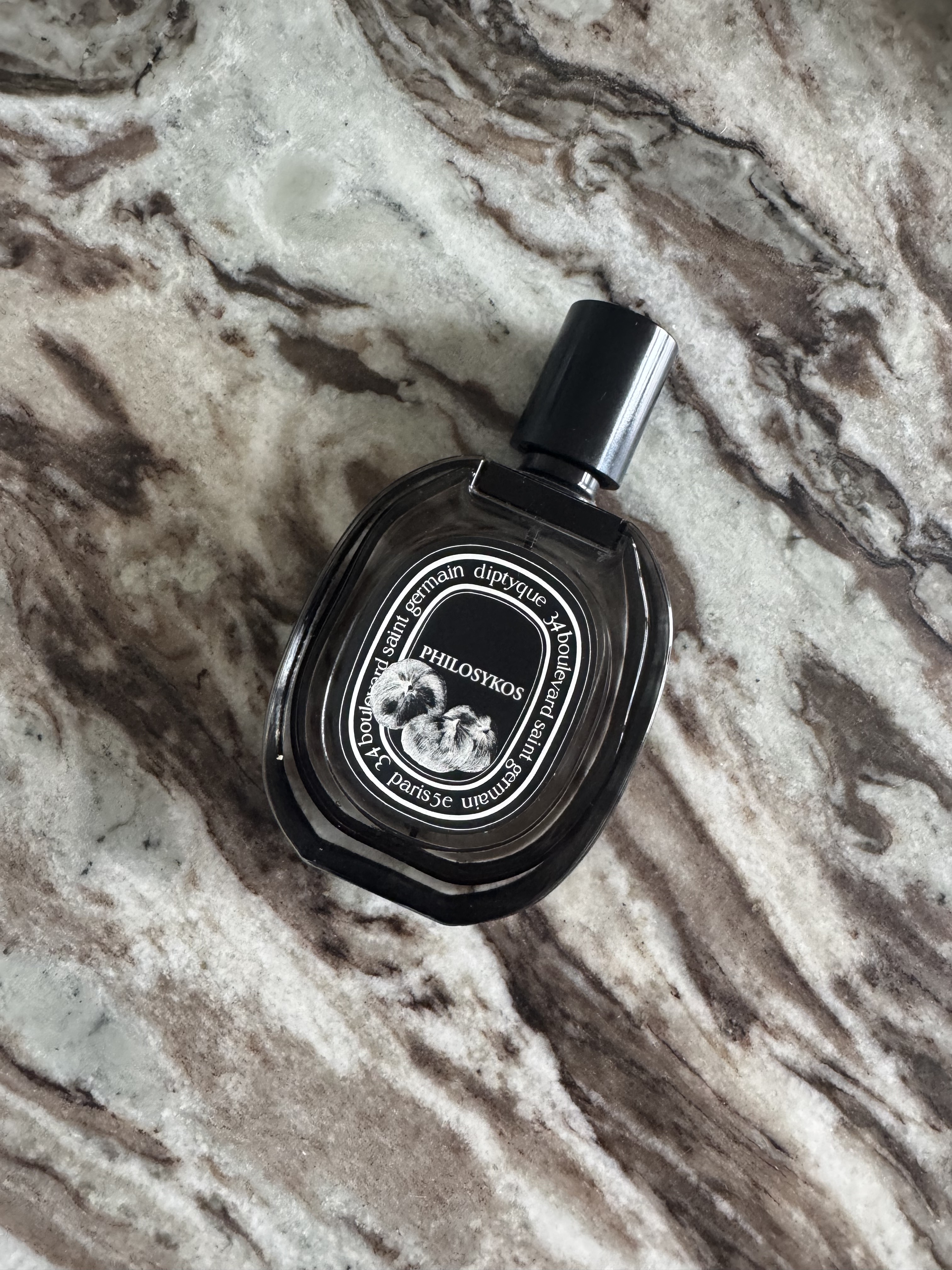 A bottle of Diptyque Philosykos on a marble table