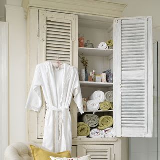 bathroom with white cupboard and throw and clothes