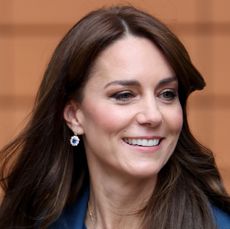 Kate Middleton wearing a blue jacket and sweater smiling