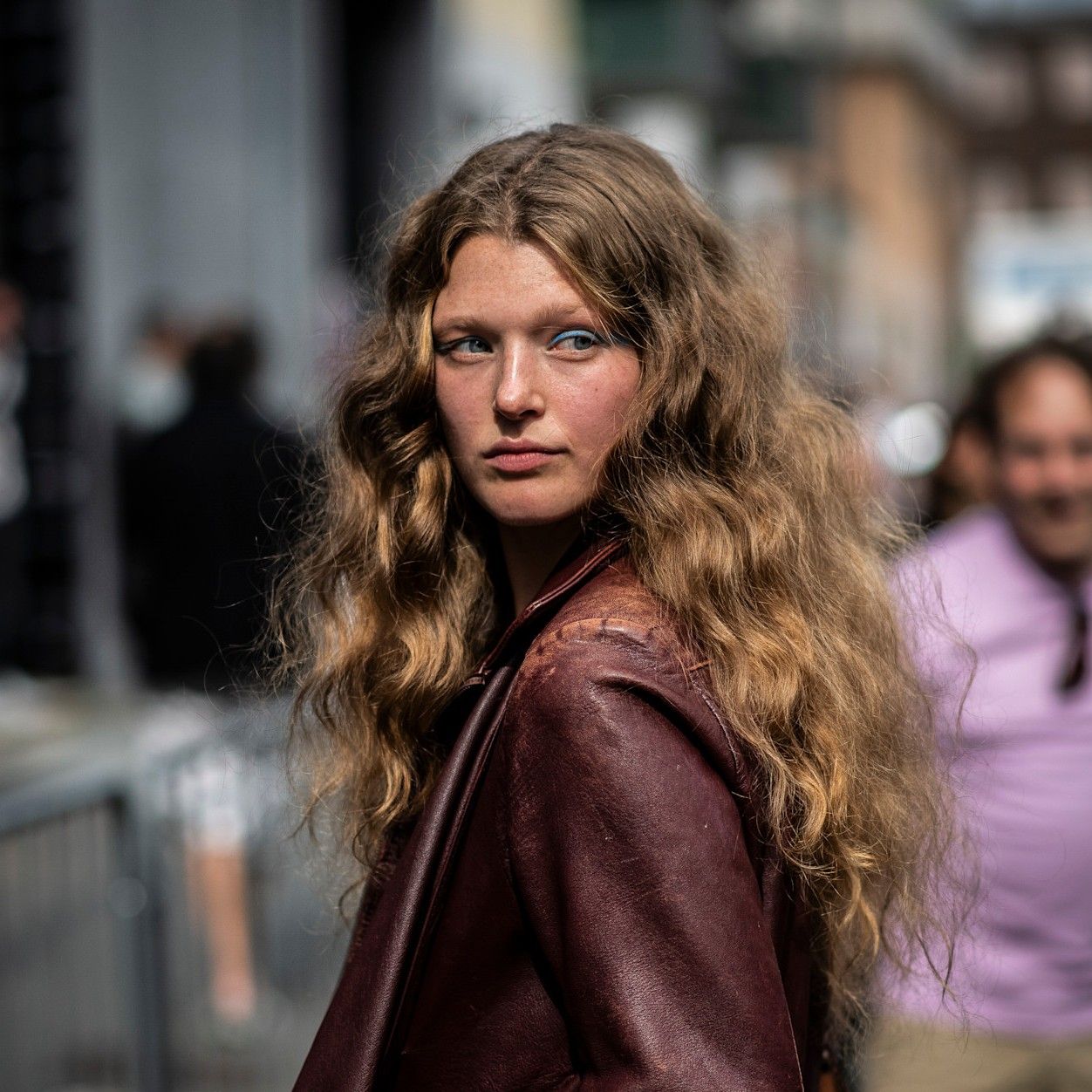 A model with curly, freshly cleaned hair standing in the street.