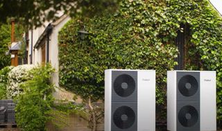 Two Vaillant heat pumps outside a cottage with a hedge growing up it